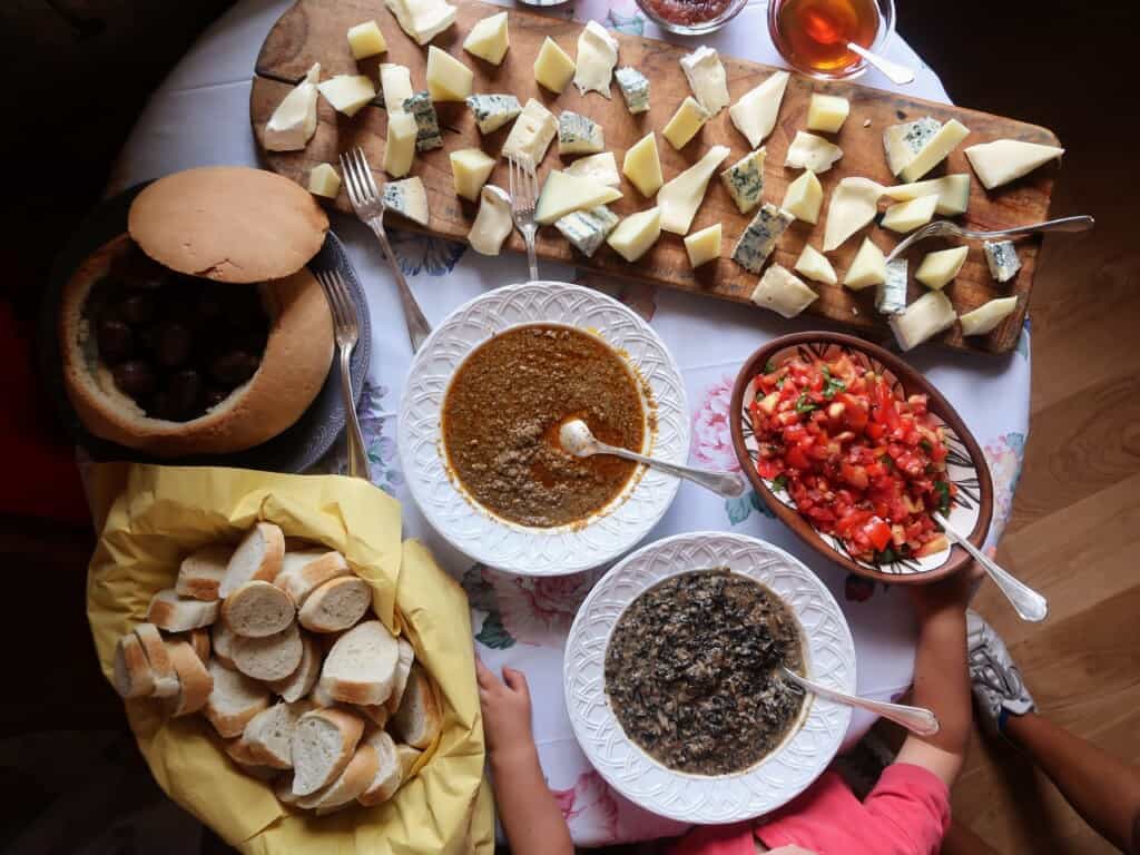 birds eye view of various Italian dishes such as a cheese board, freshly cut tomatoes to make bruschetta, bread, slices and lentils.