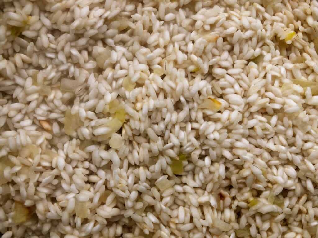 close up of carnaroli rice being cooked with rice and white wine for risotto