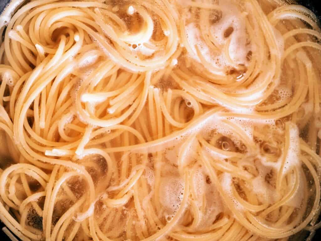 spaghetti being cooked in a large pot of water from birds eye view
