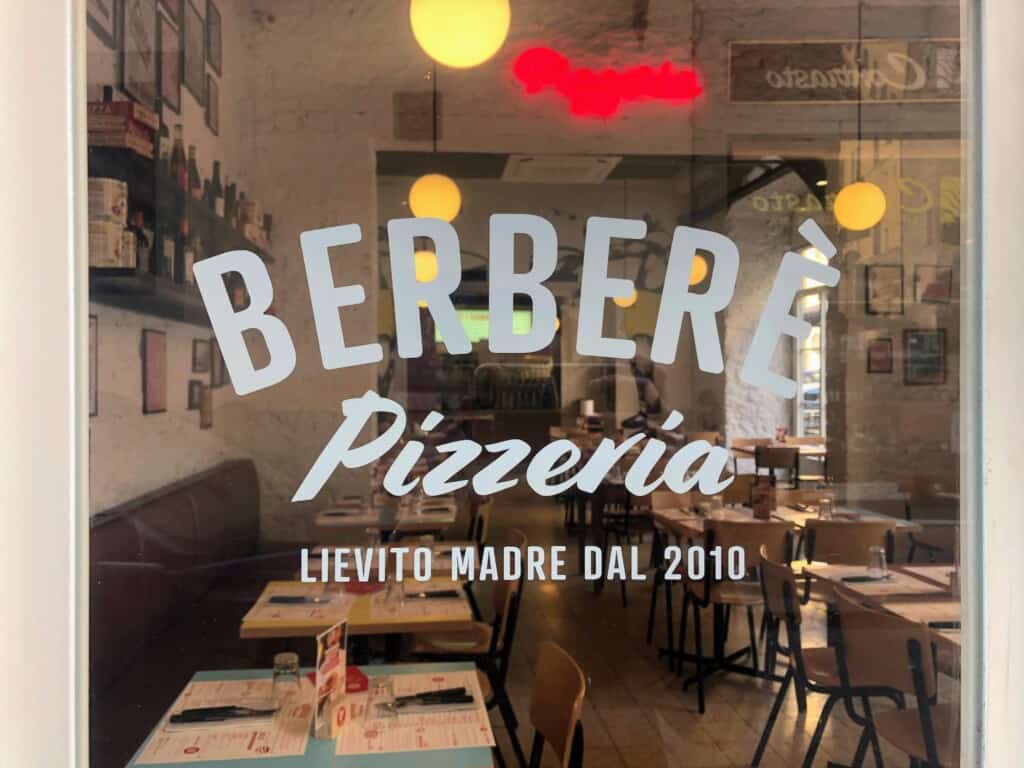close up of glass window with berbere pizzeria written in white.