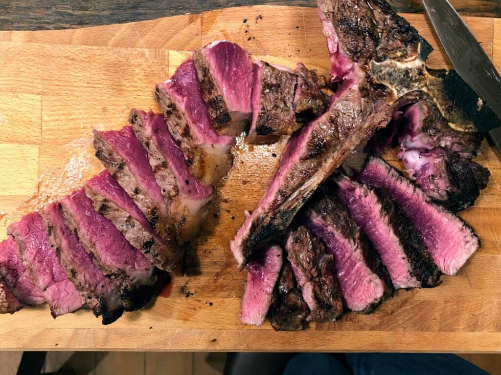 bistecca fiorentina sliced on the angle, served rare on a wooden cutting board