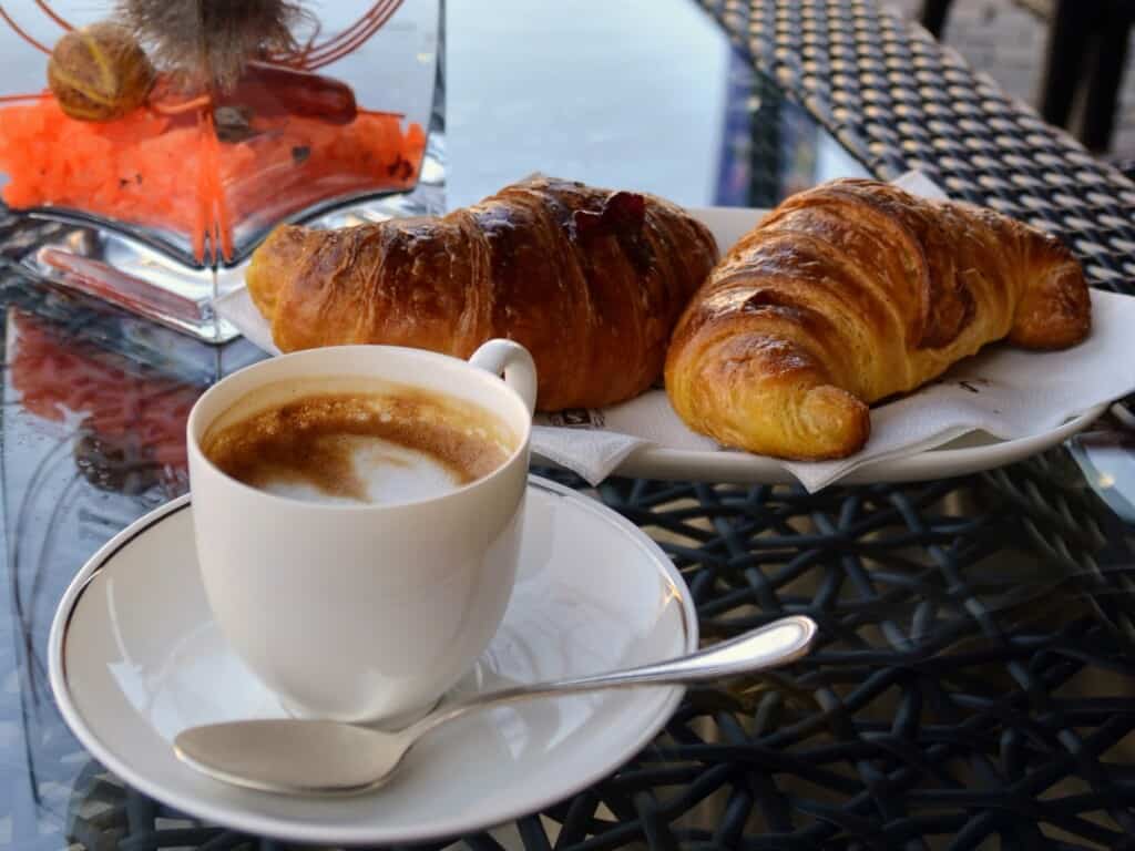 caffe macchiato with two pastries in the background on a black table