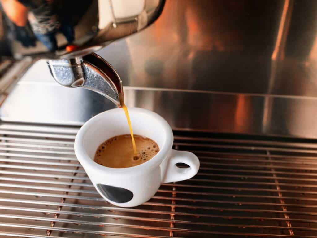 small white espresso cup under drip machine from top view