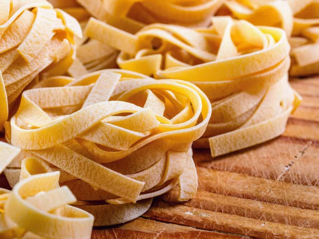 close up of homemade nests of tagliatelle on a wooden cutting board