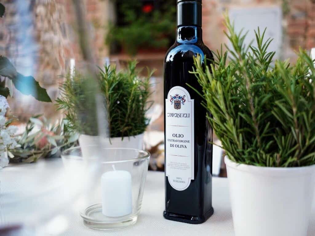 olive oil sitting on a tabel with rosemary, herbs, and a candle in Tuscany, Italy