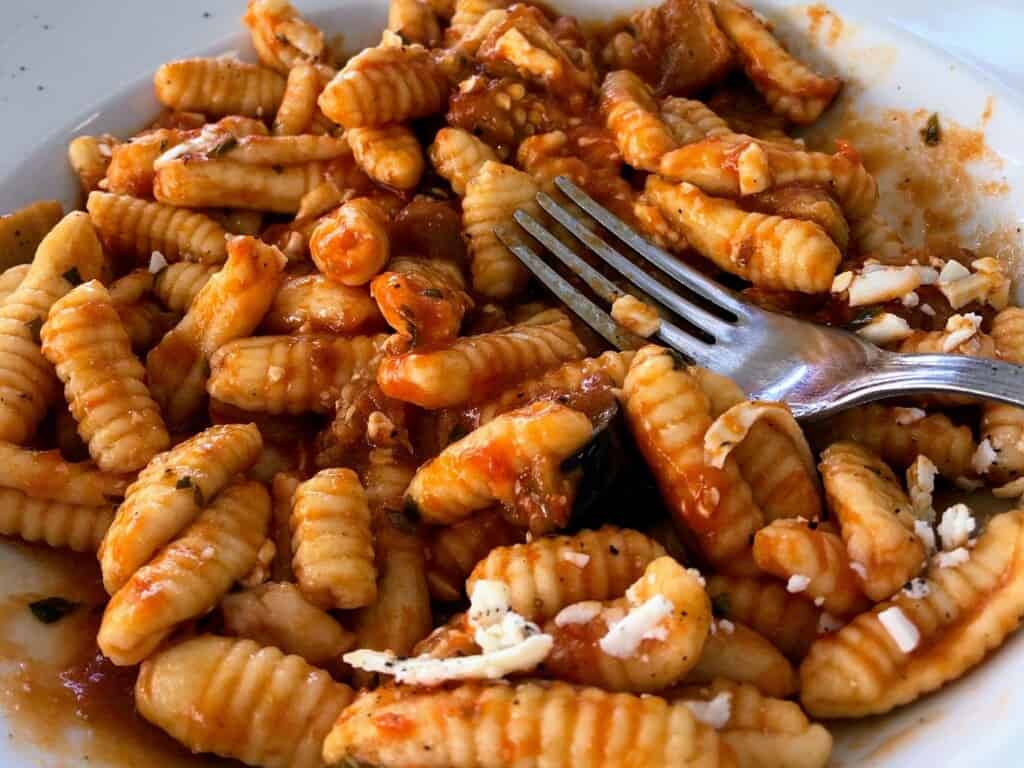 top angled view of pasta alla norma made with cavatelli with a fork in the middle