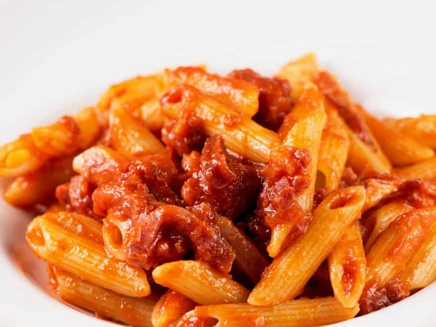 zoomed in pasta amatriciana with penne and white background