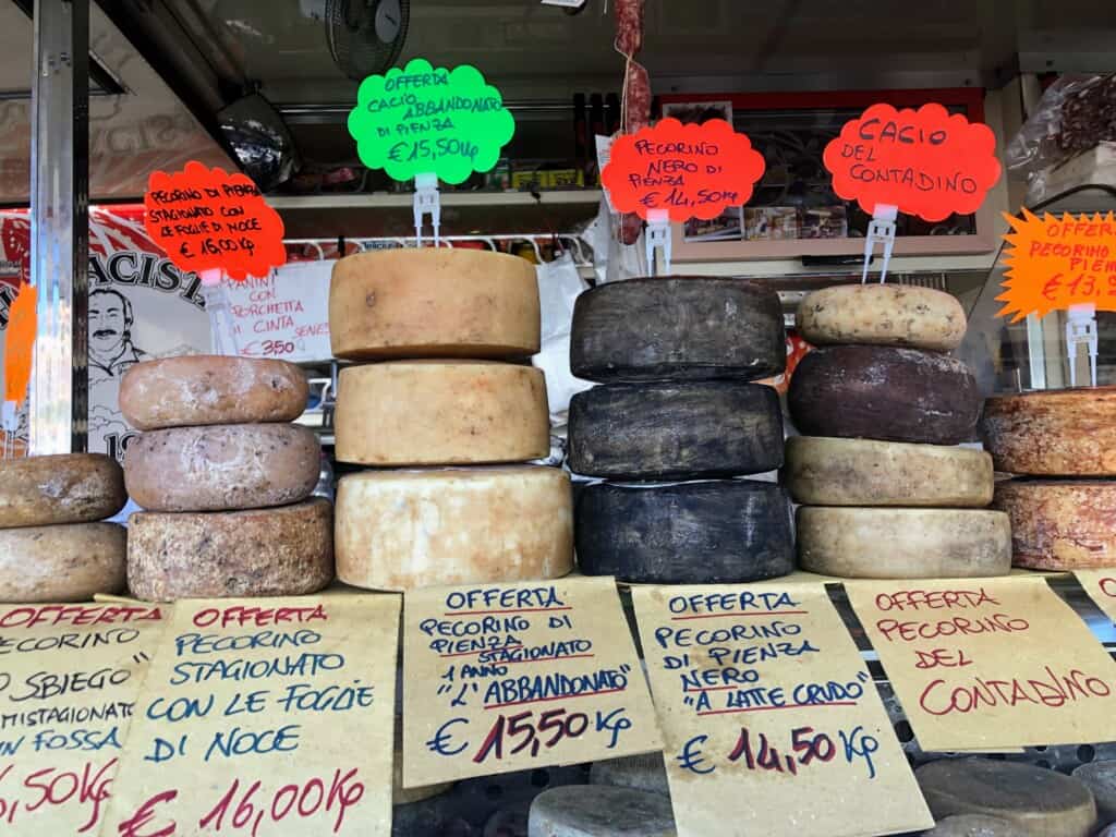 truck full of different pecorino cheeses for sale with signs written by hand on cardboard indicating prices close up