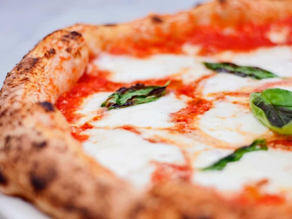 zoomed in angle shot of pizza margherita garnished with fresh basil
