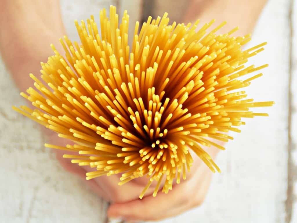 zoom in of spaghetti held in hands from birds eye view