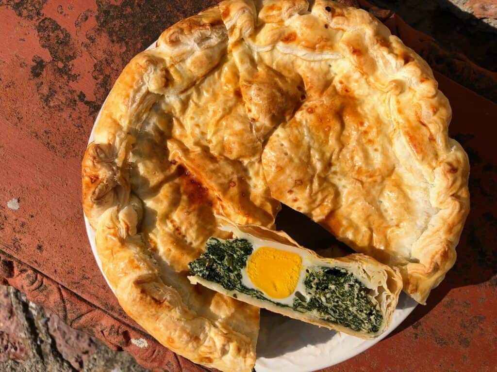 Whole torta pasqualina (Italian Easter pie) with a slice cut out.