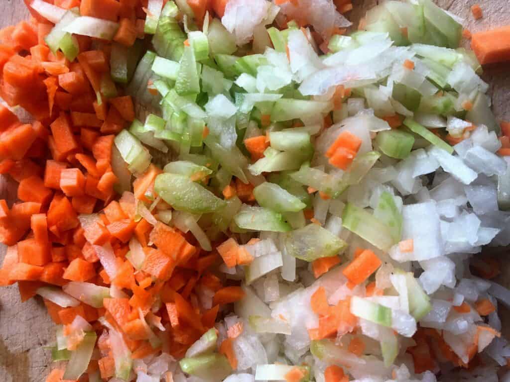 Close up of Italian soffrito ingredients - carrots, onions, and celery, all chopped.