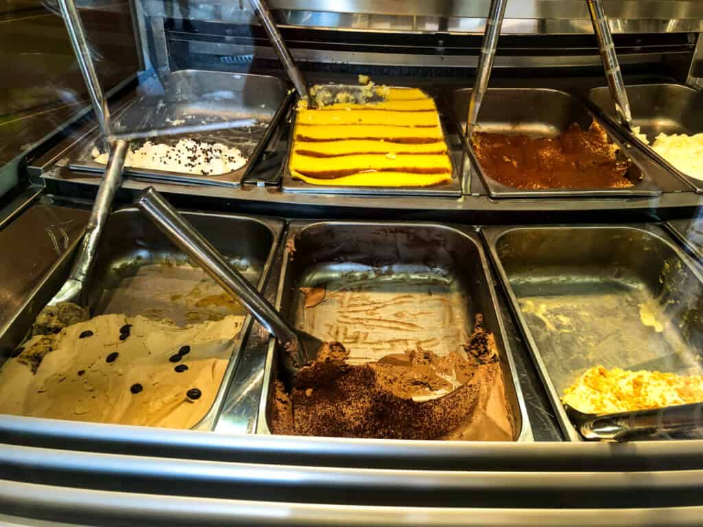Close up of gelato in metal tins at a gelateria in Italy.