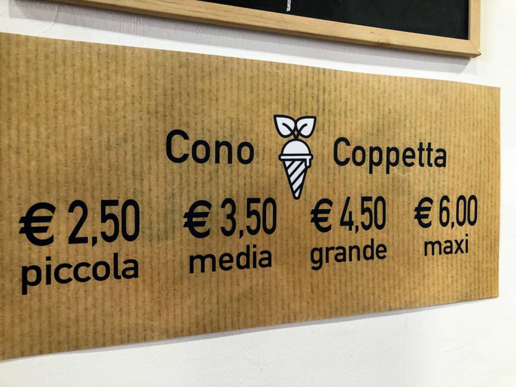 Brown ign with prices for cones and cups of gelato in Italy.