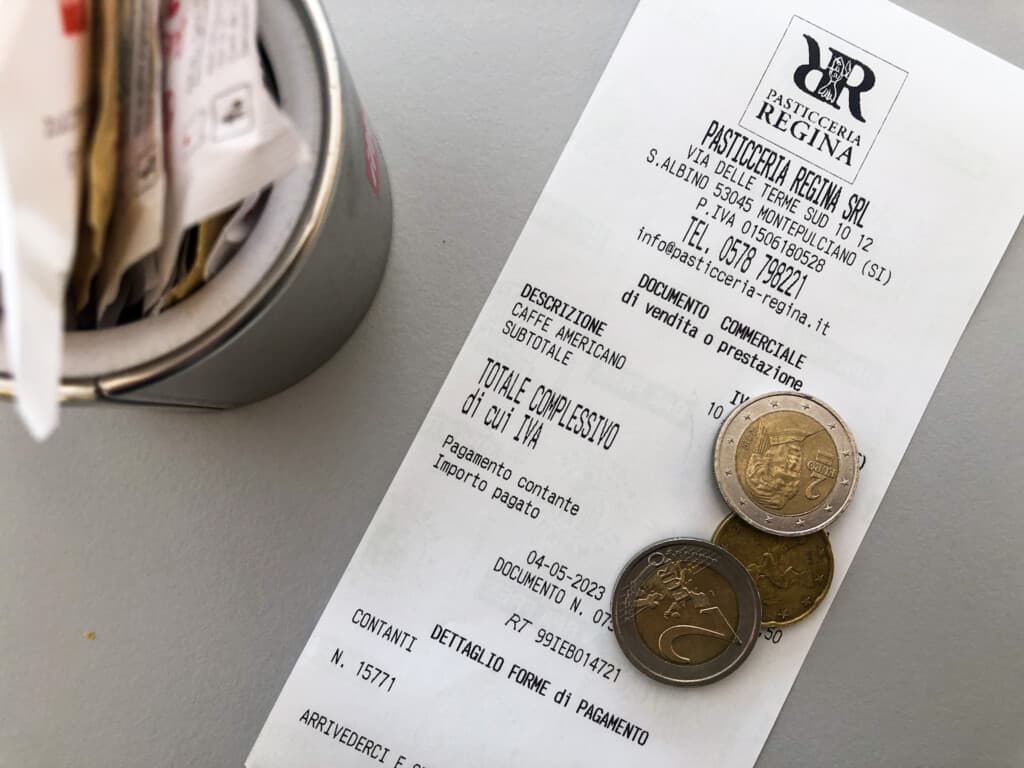 Close up of a receipt for Pasticceria Regina in Italy with a few coins on top.