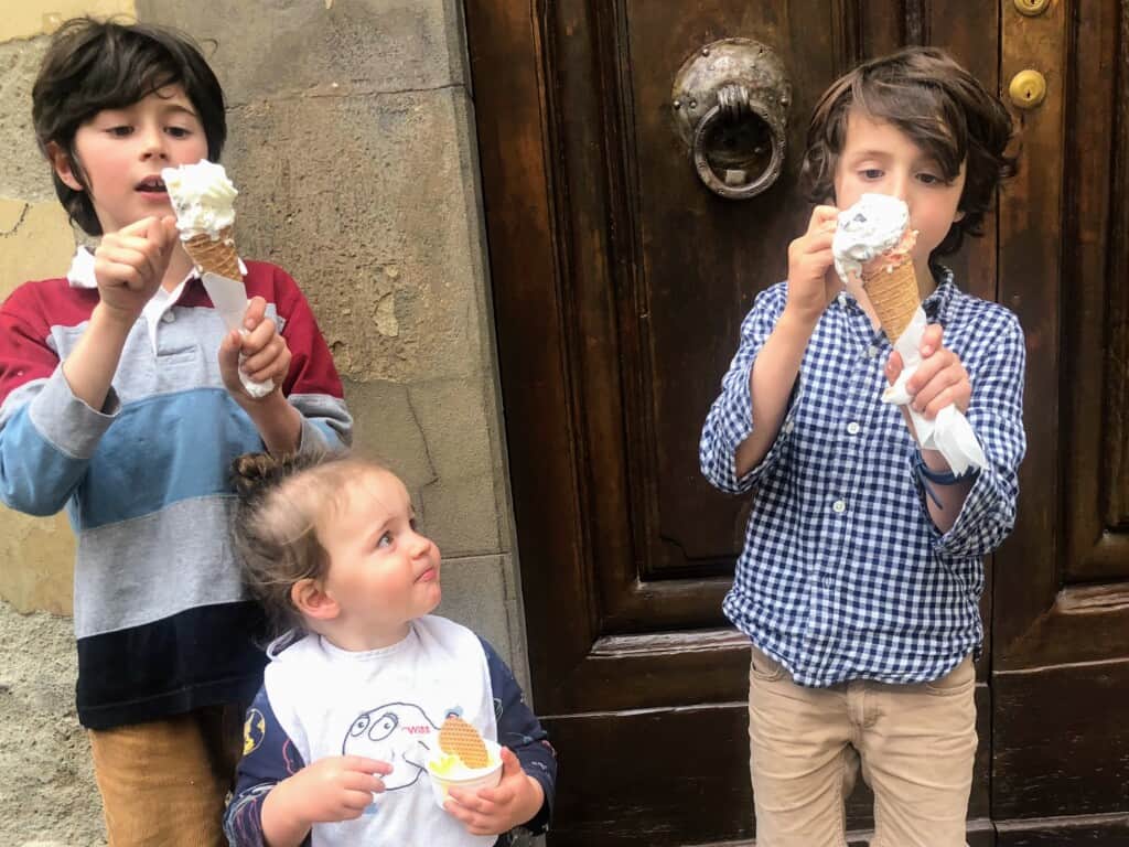 Young boys eating cones and cups of gelato.
