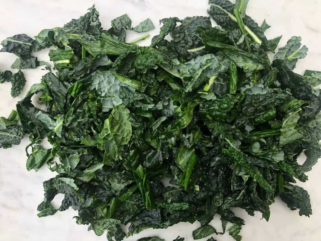 Pile of chopped cavolo nero on marble counter.