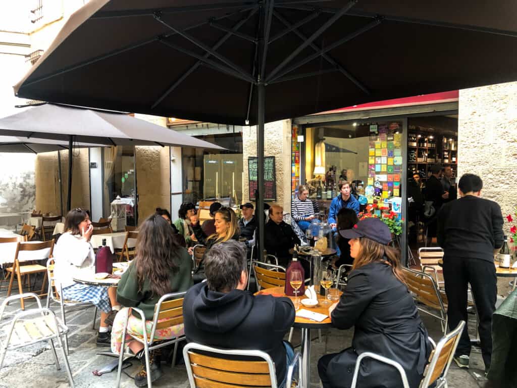 People sitting at tables under umbrellas and having aperitivo in Italy.