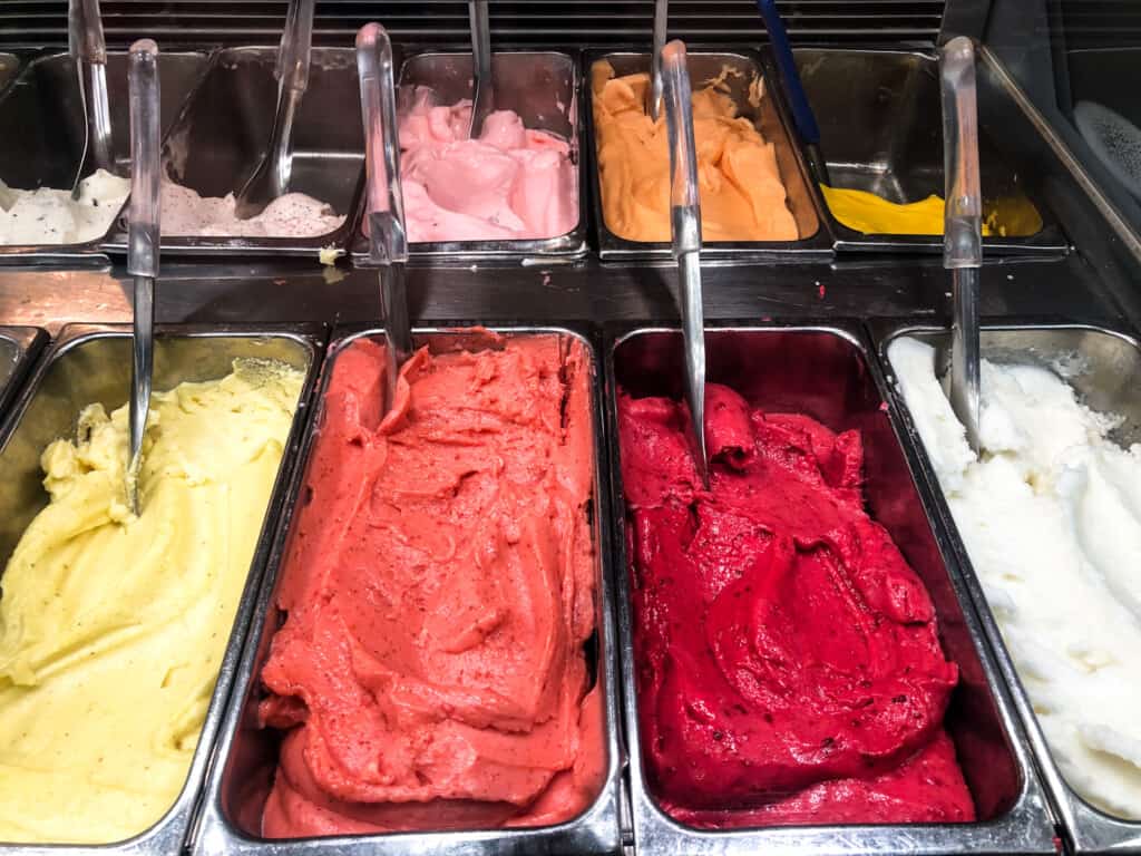 Close up of colorful gelato in metal bins in a gelateria in Italy.