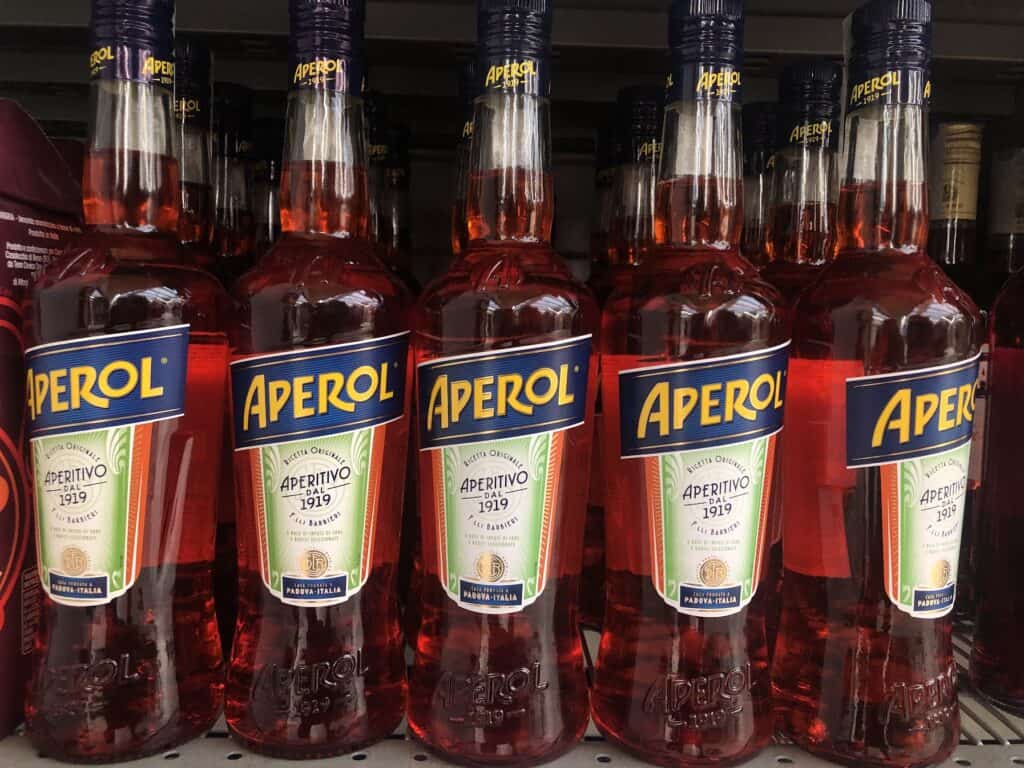 close up of 5 bottles of aperol for sale on a shelf from side view
