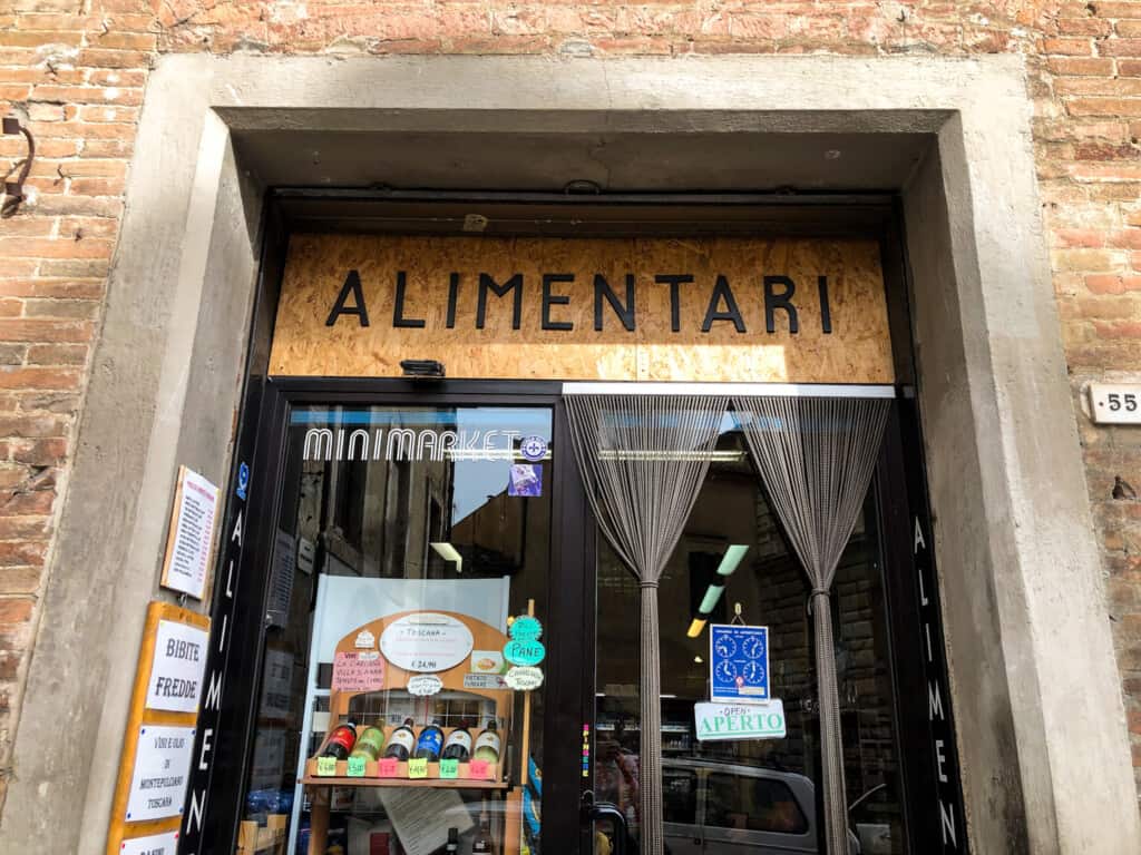 street view of a large glass storefront with brown sign written alimentari in black letters above doorway