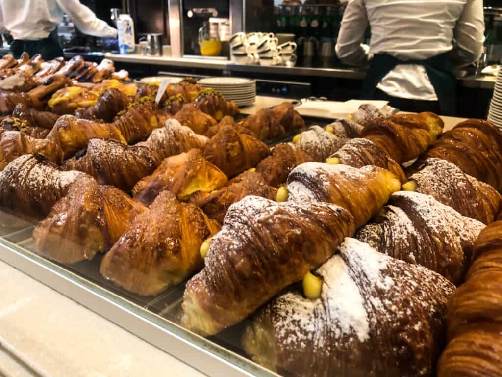 side view of glass case displaying various pastries at an italian bar