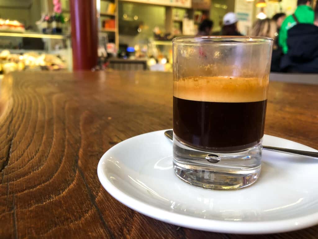 side view of a caffe in vetro in a small white glass on a white saucer on a wooden table

