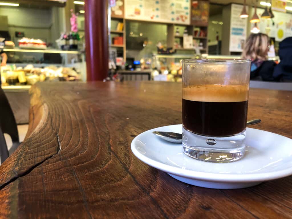side view of a caffe in vetro in a small white glass on a white saucer on a wooden table