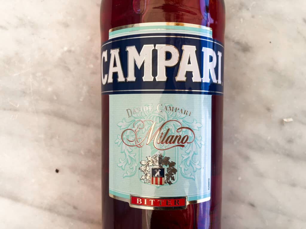 Close up of bottle of Campari on a marble surface.