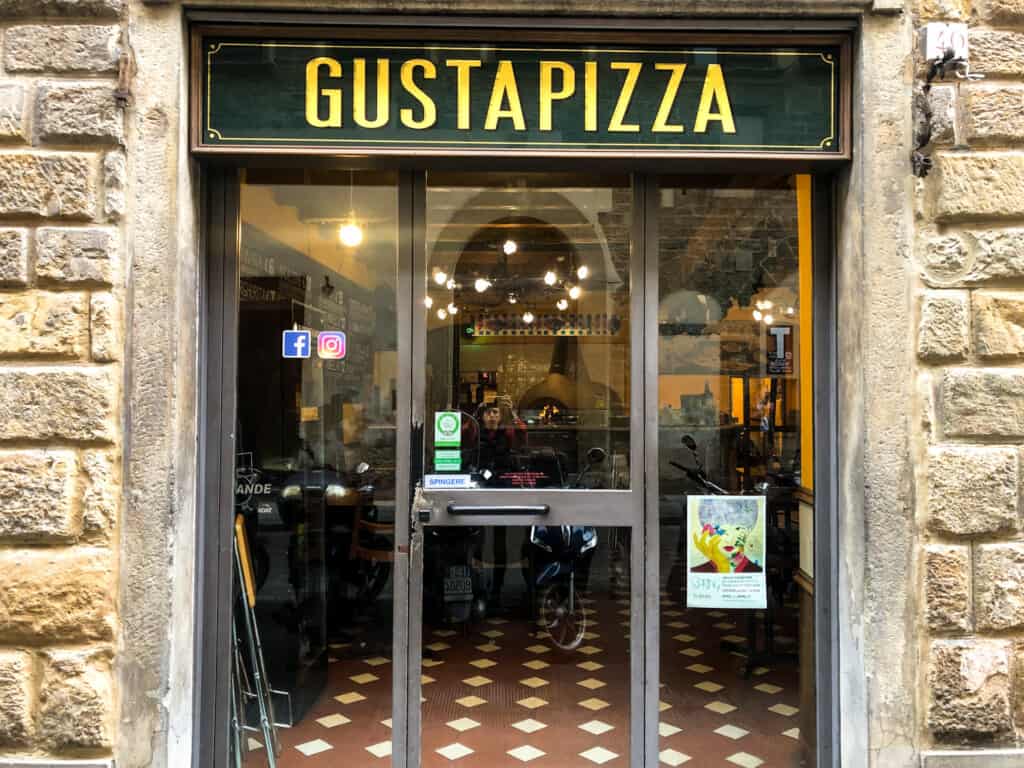 street view of gusta pizza with open doors and a green sign with gold writing on top