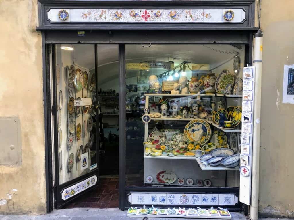 Front entrance to a ceramics store in Italy. You can see ceramics in the window display and outside on the ground in front of the shop.