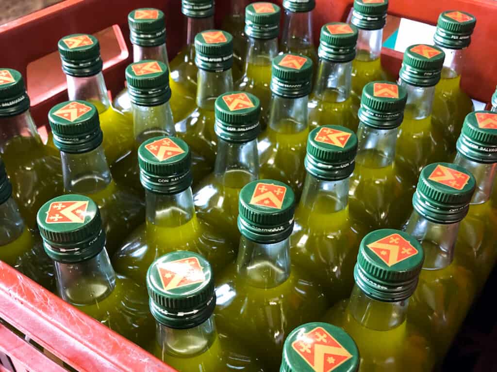 top view of several bottles of olive oil freshly bottled with bright green oil and green tops in a red case