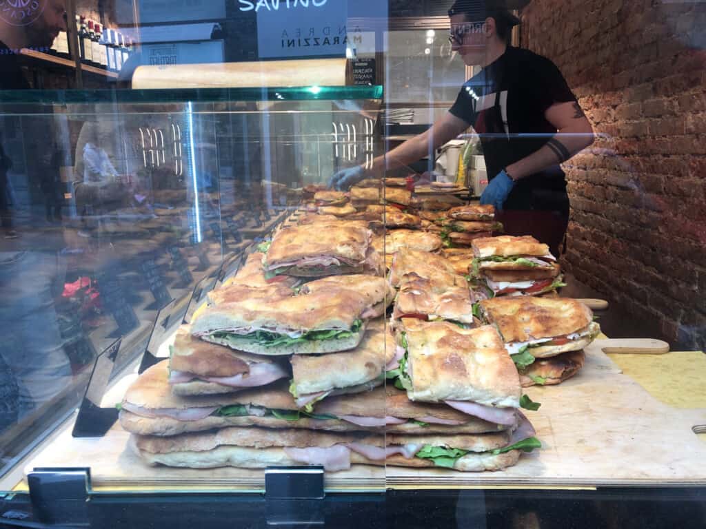 glass case with many schiacciata sandwiches stacked high.