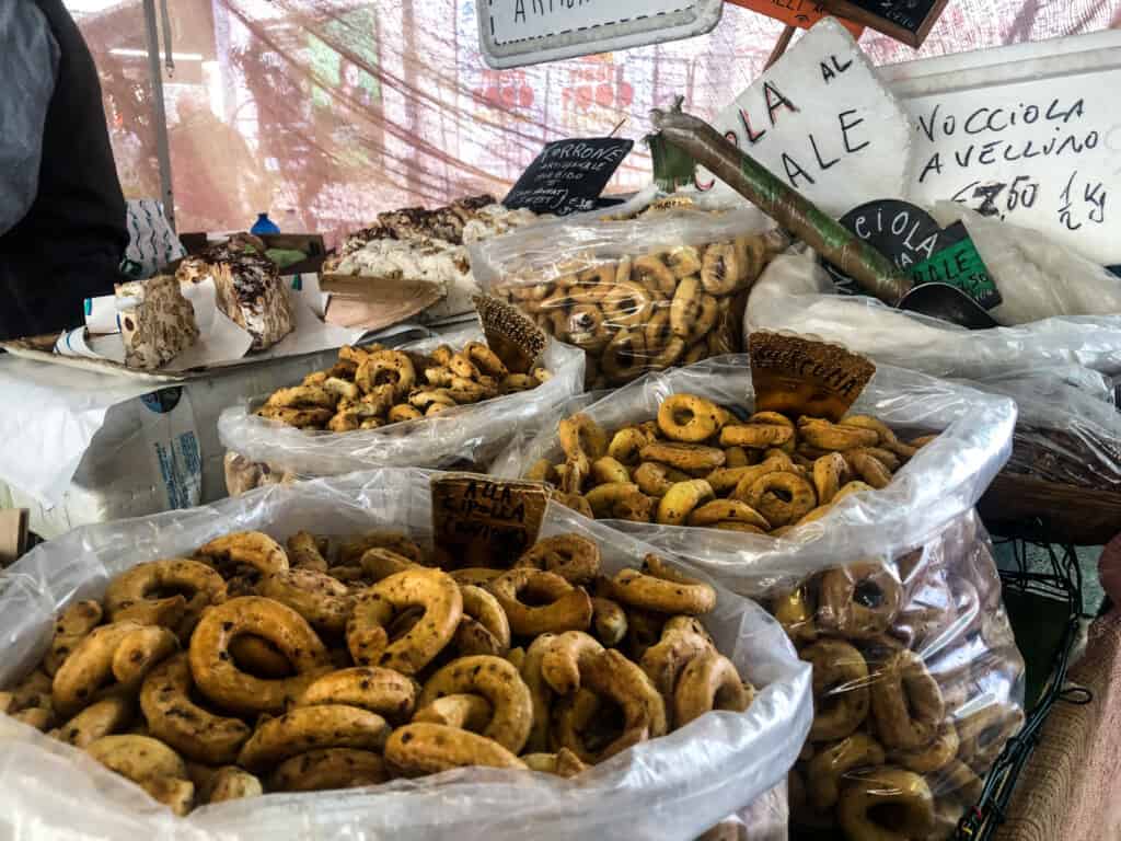 plastic bags full of various taralli flavors at an open air market in italy from side view