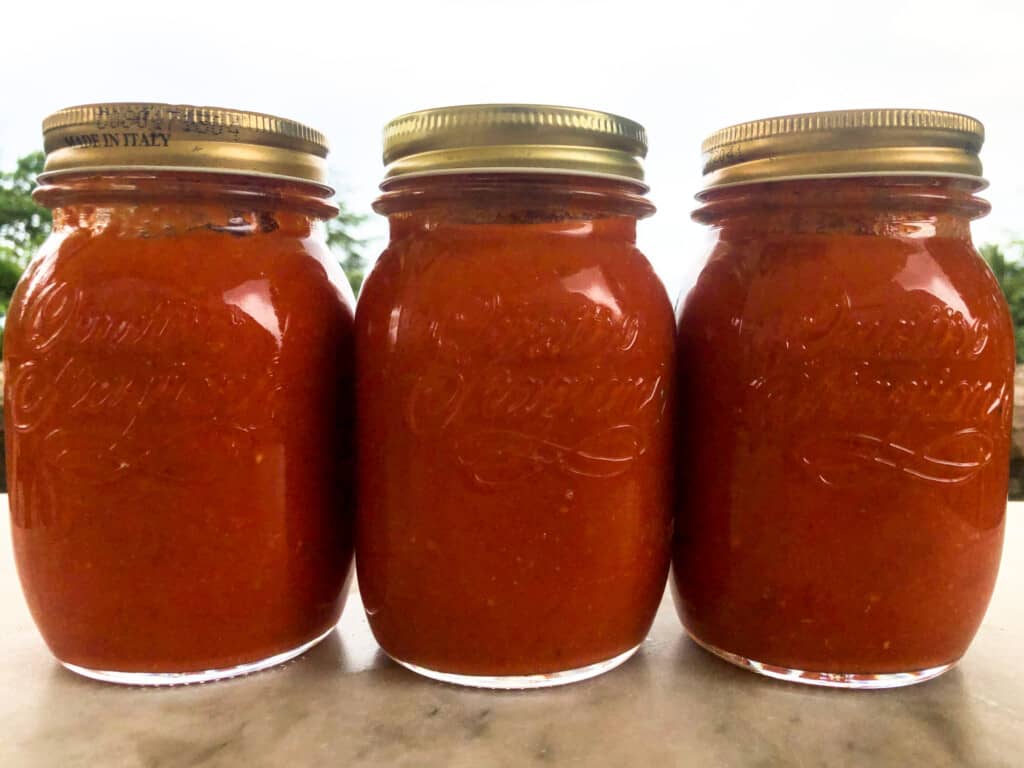 Jars of italian pomodoro sauce with lids on grey marble.