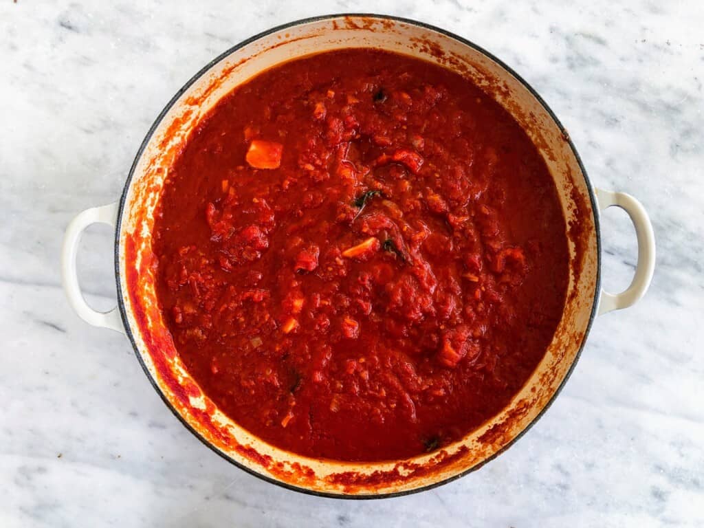 Top view of pot of Italian pomodoro sauce on marble surface.