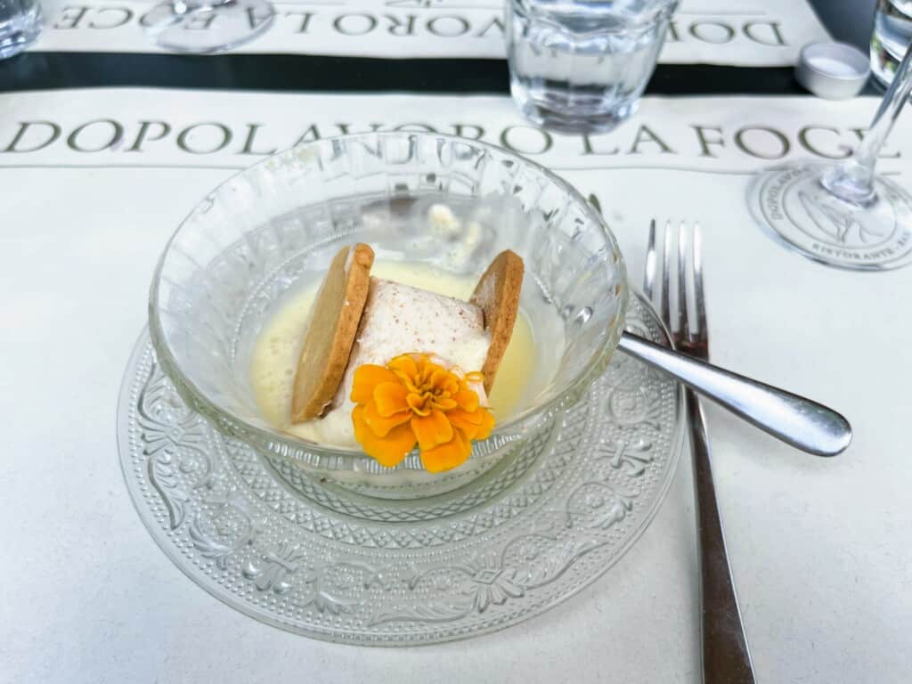 Close up of glass dish of semifreddo. It's decorated with a small yellow flower.