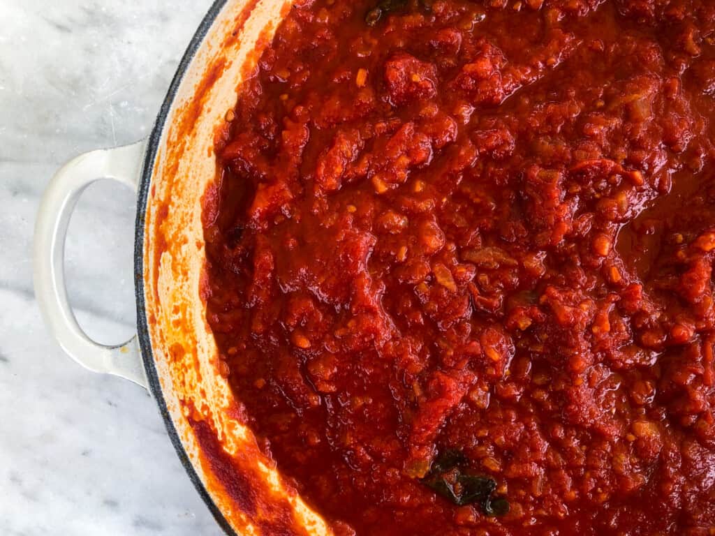 Close up of part of a pot of Italian pomodoro sauce that has basil in it.