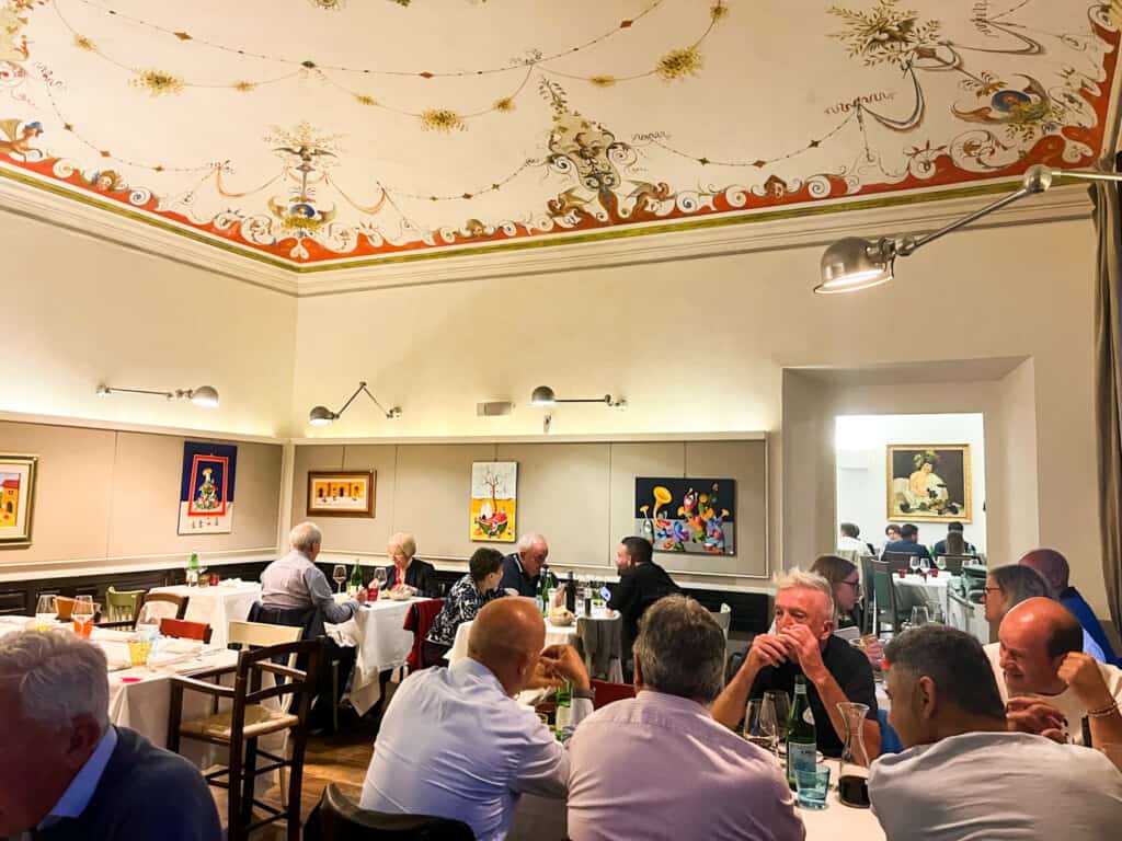 Diners inside Ristorante Coppetta. You can see people eating at tables. The ceiling is painted with delicate decorations.