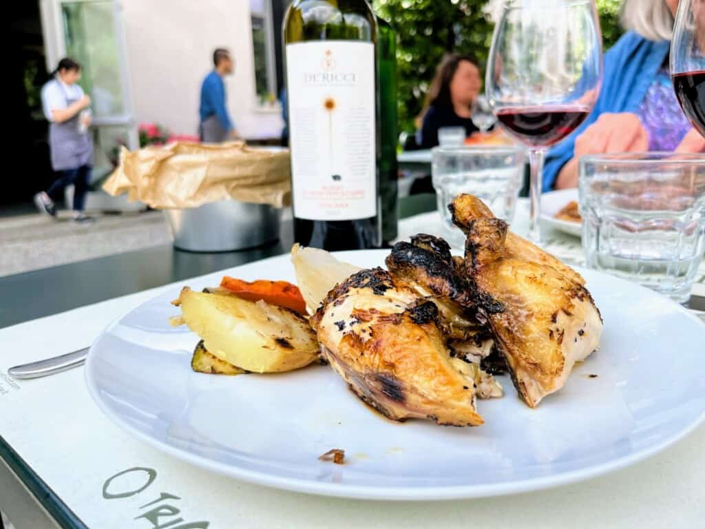 Plate of roasted chicken at an outdoor table at a restaurant in Italy.