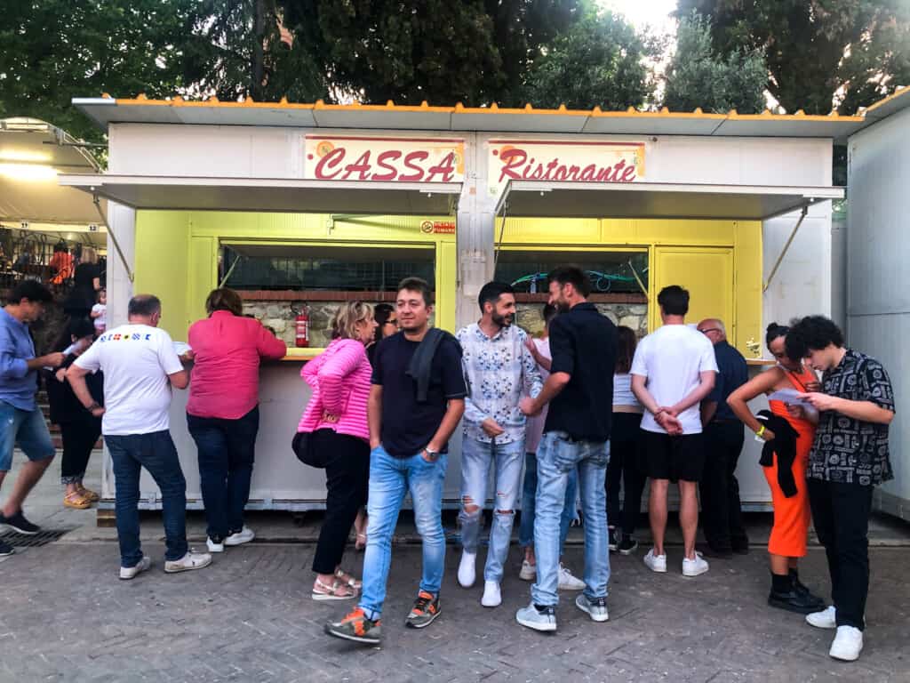 The cash register booth at a sagra in Italy. People are waiting in line to pay.