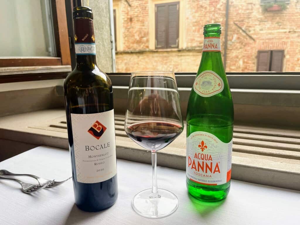 Bottle of red wine and water on a table at a restaurant in Italy.