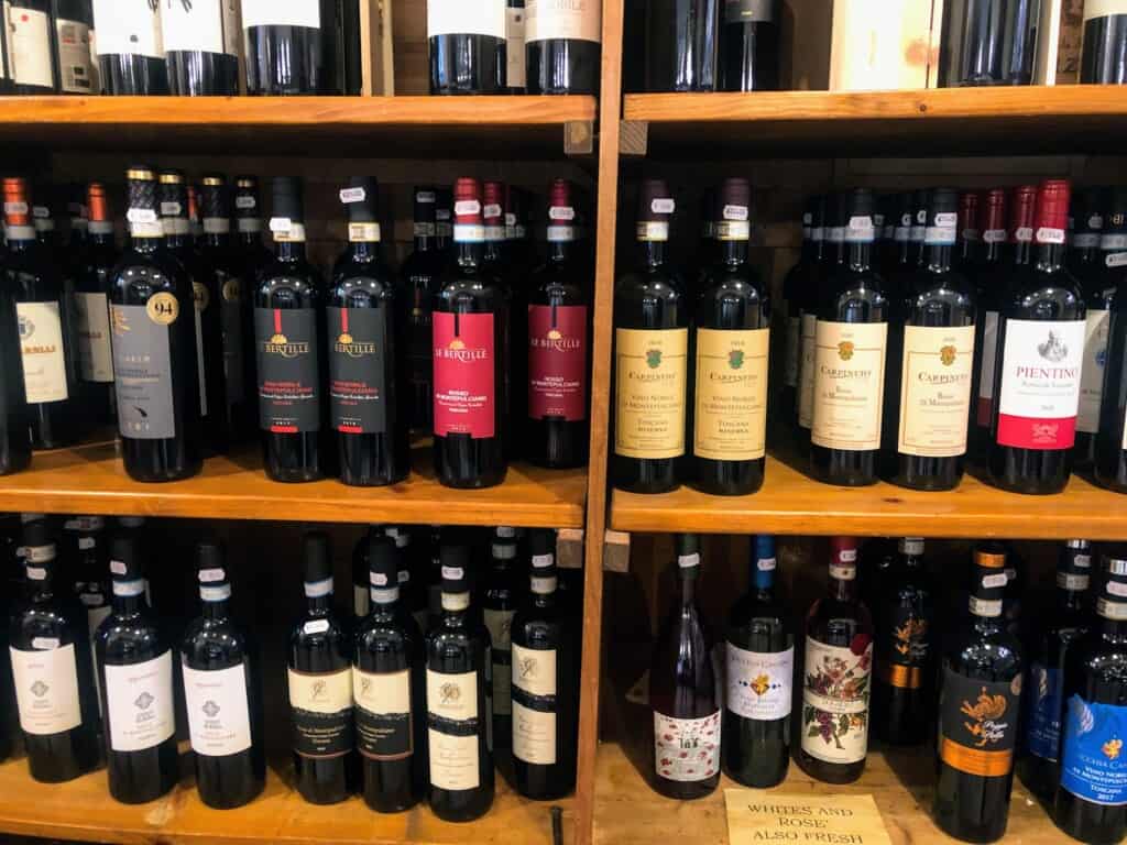 Bottles of wine on wooden shelves at a wine shop in Italy.