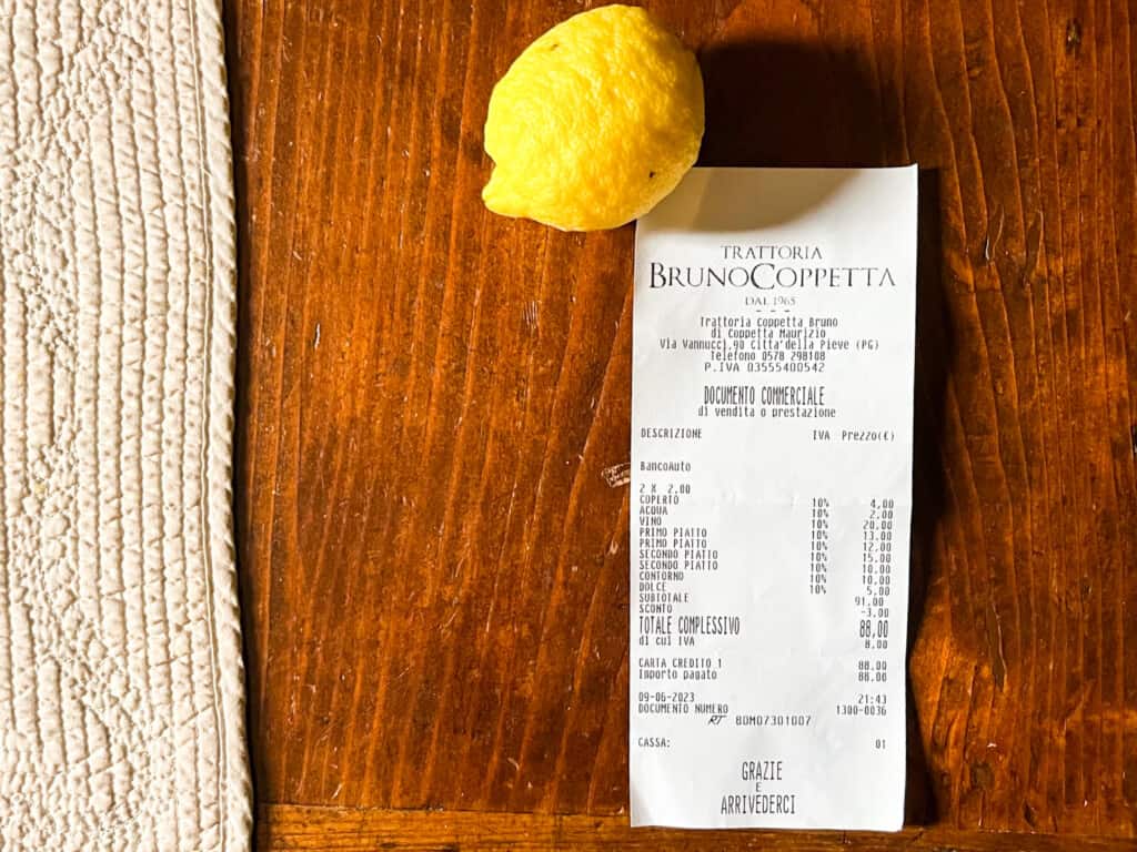 Italian restaurant bill and lemon sitting on a table.