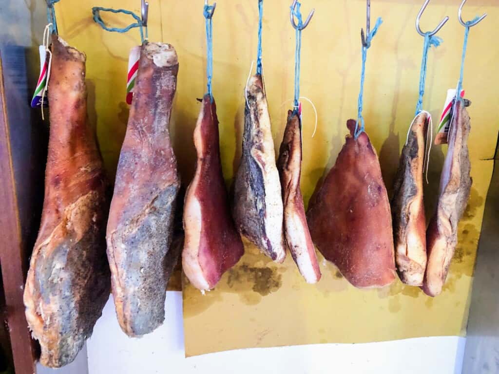 Prosciutto legs hang from hooks in Italy.