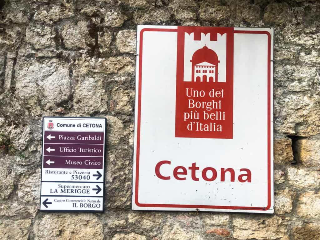 Close up of red and white sign with 'Uno dei Borghi più belli d'Italia - Cetona.'