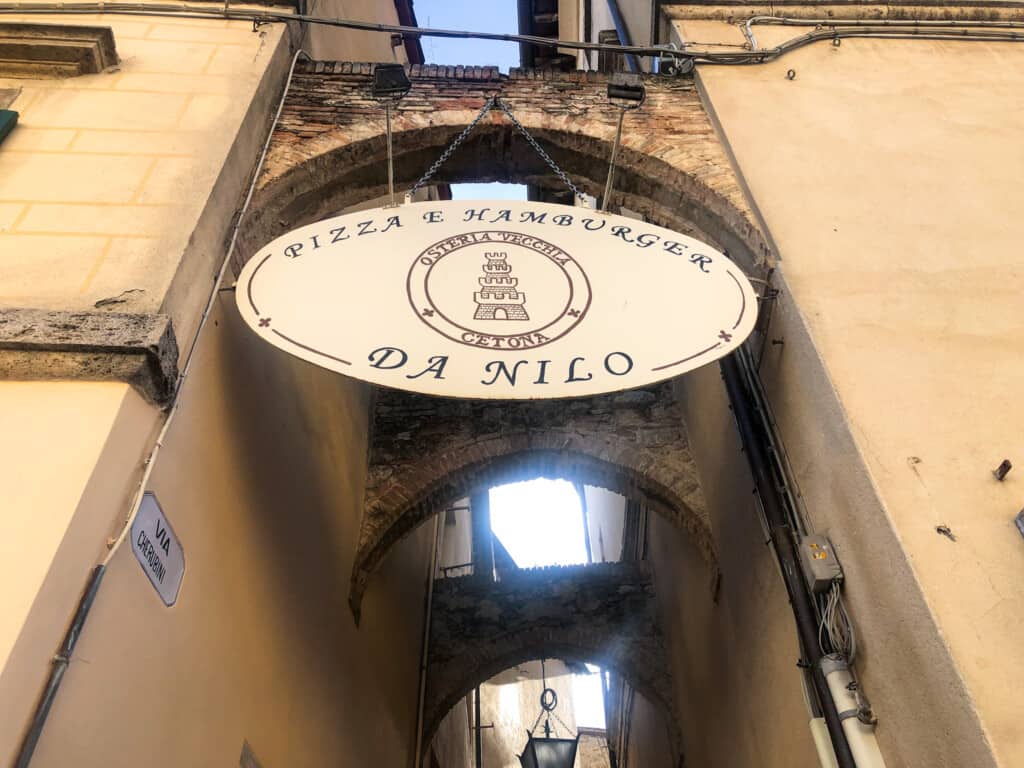 Sign hanging from Italian arch. It says Pizza e Hamburger da Nilo