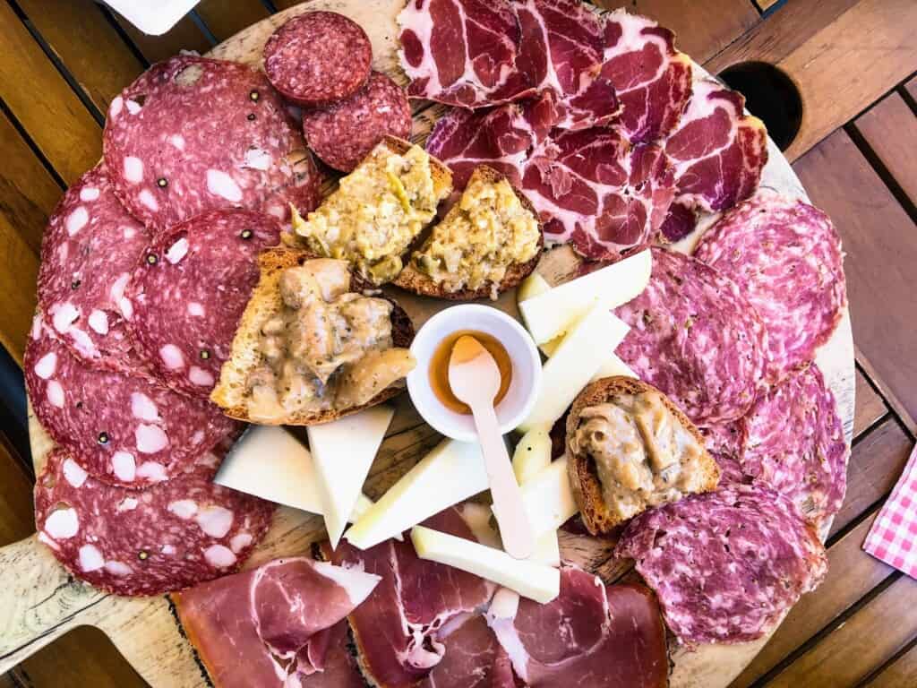 Close up of Italian charcuterie board - called a tagliere - with cured meats, sliced cheeses, and bread with toppings.