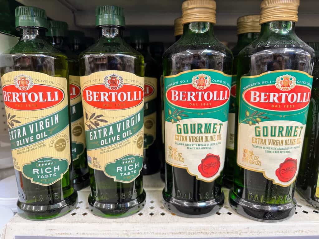 Bottles of Bertolli olive oil on grocery store shelf.