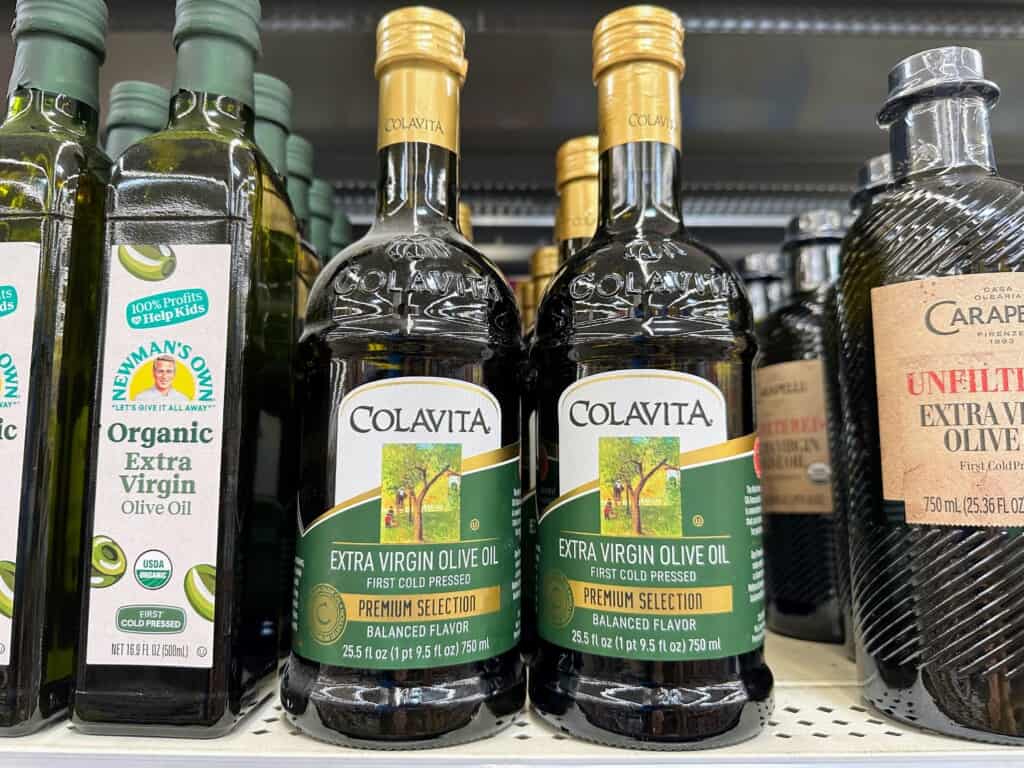 Bottles of Colavita olive oil on grocery store shelf.